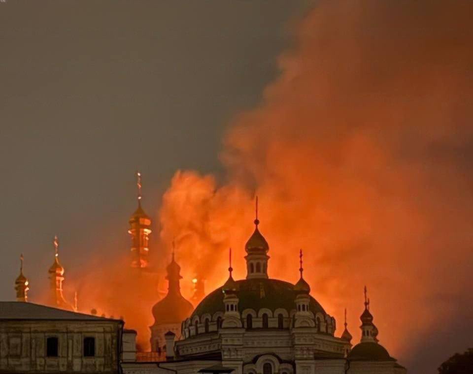 The gilded domes of the Kyiv-Pechersk Lavra silhouetted against flames and a large orange-lit smoke plume during the fire of 15 June 2026.